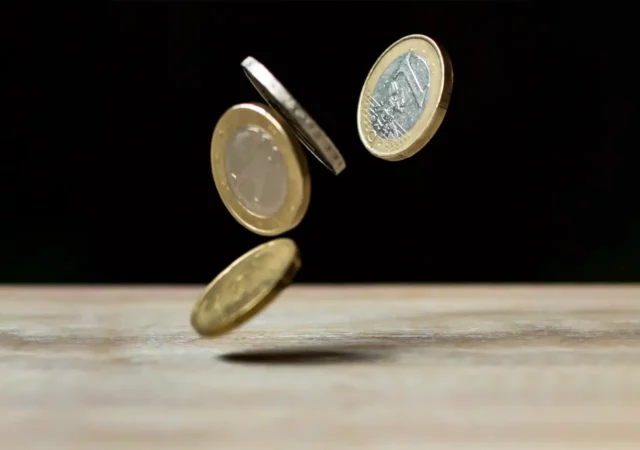 Münzen fallen auf einen Holztisch
